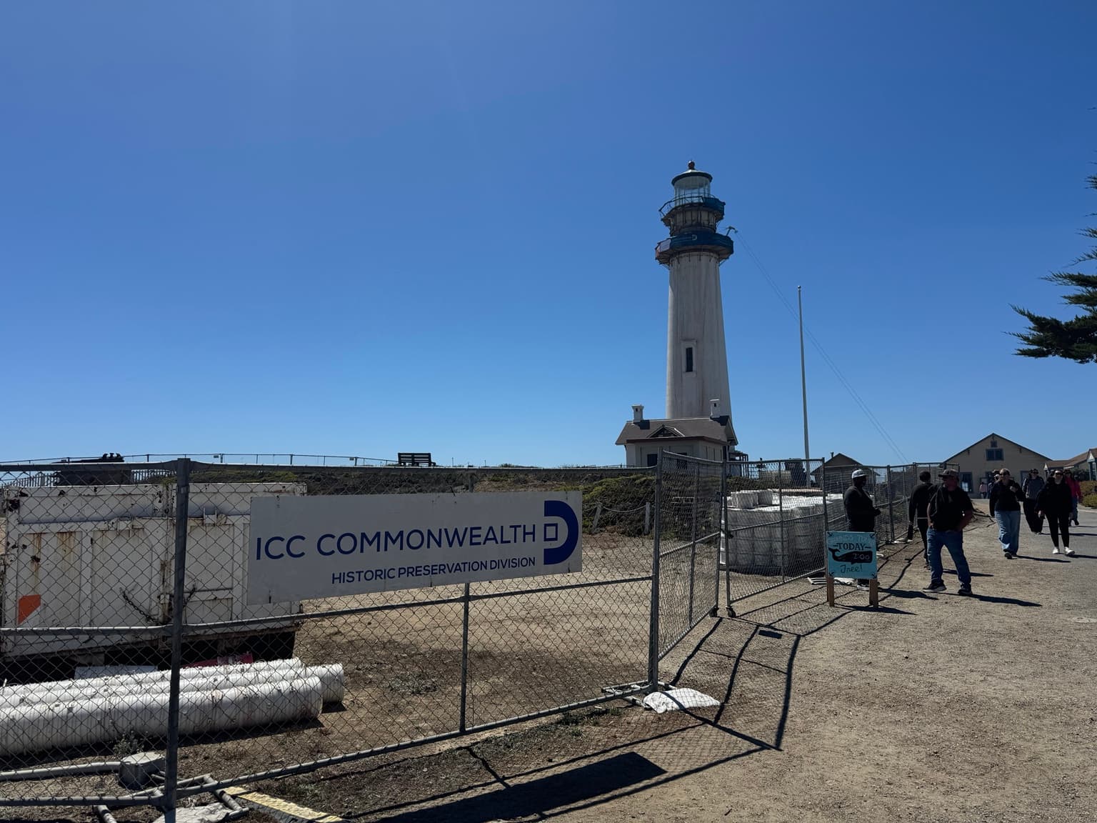 Pigeon Point Lighthouse during restoration, with construction fencing and visitors on the open grounds