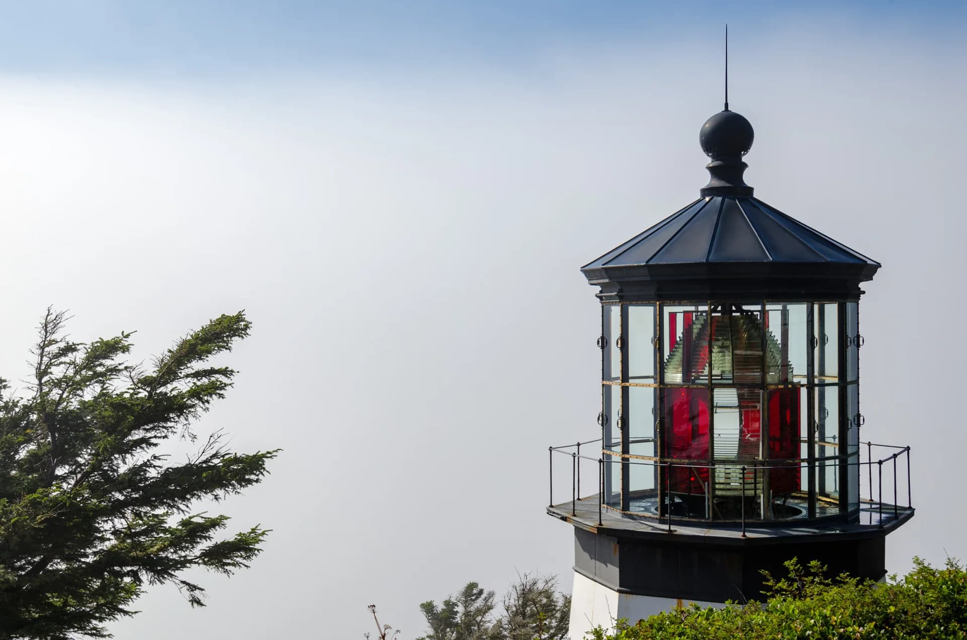 Close view of the Cape Meares lantern and red glass lens against the ocean.