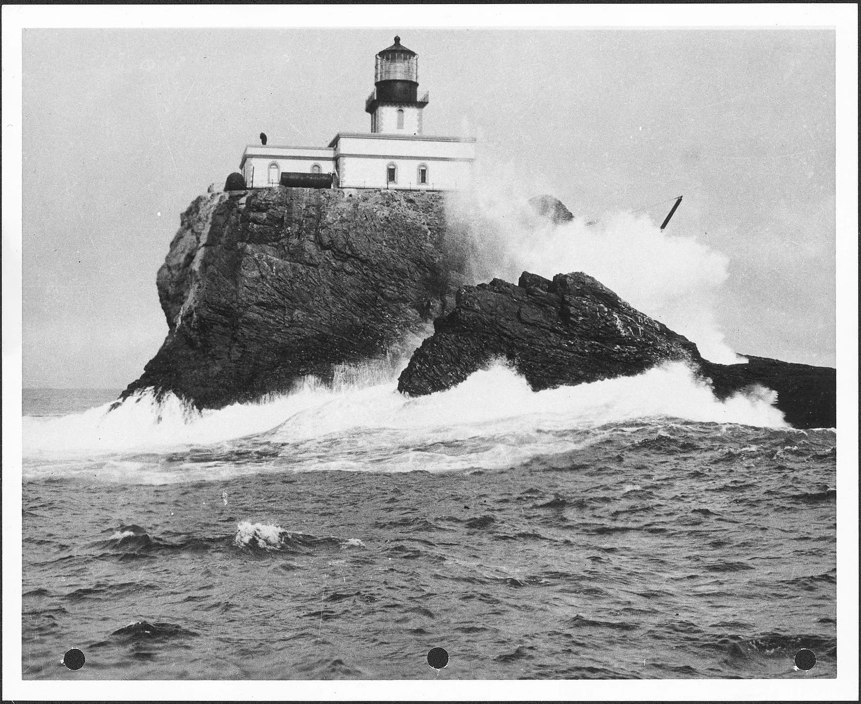 Historic photograph of Tillamook Rock Lighthouse with waves breaking against the rock.
