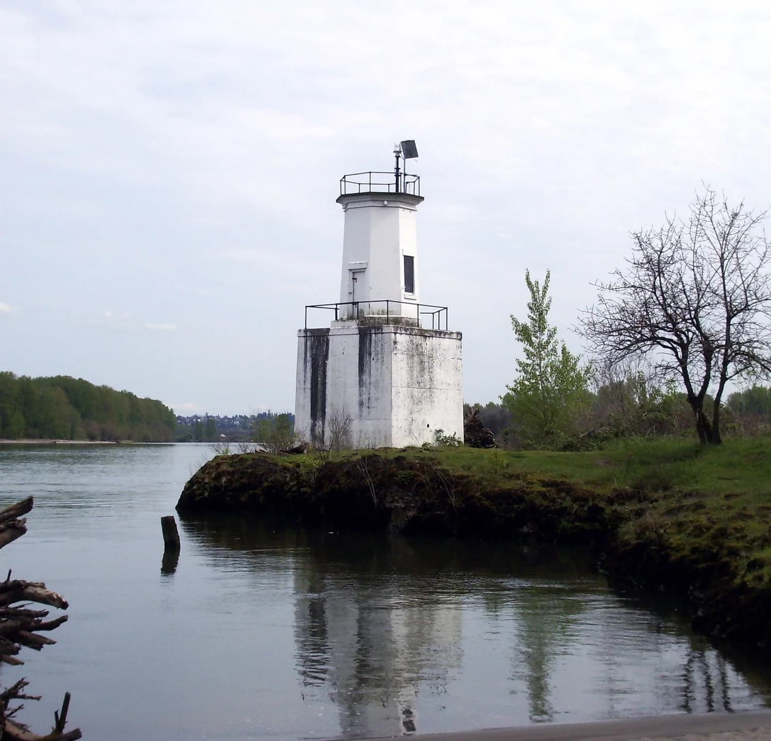 White square lighthouse tower beside the Columbia River shoreline.