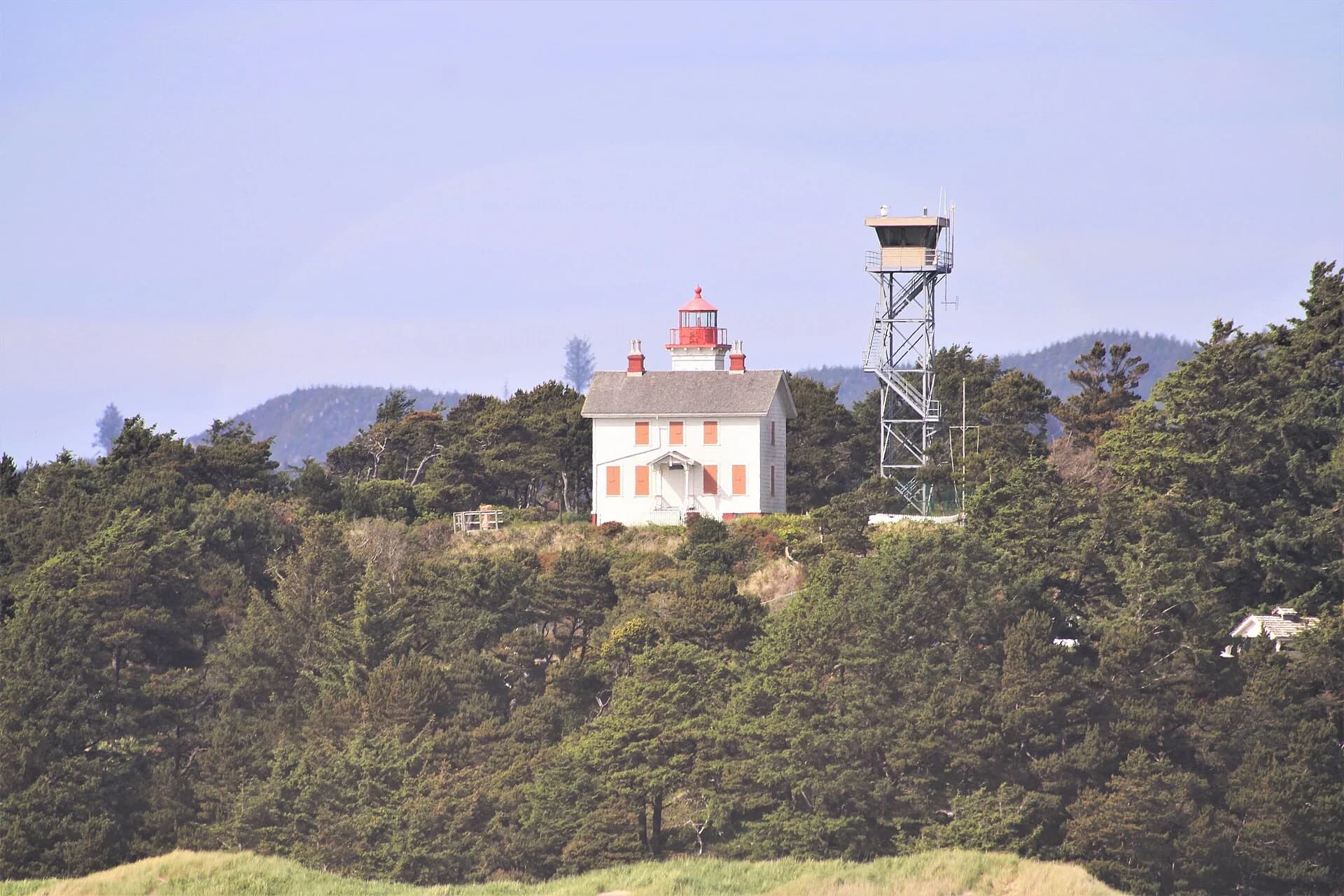 White wooden two-story lighthouse keeper's house with a small lantern tower on the roof, Newport, Oregon.